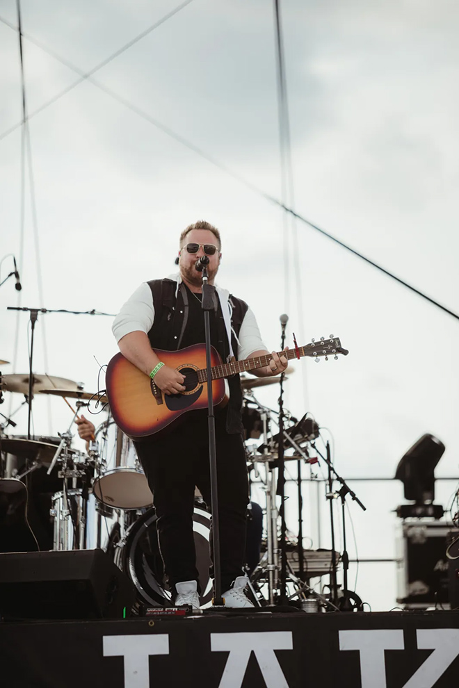 Jake Nelson on stage singing and playing acoustic guitar