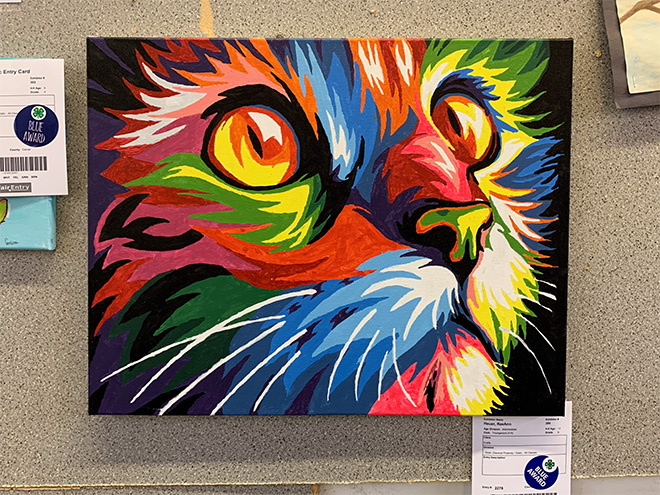 a brightly colored painting of a cat on display in the 4-H building