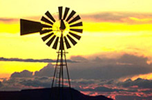 a windmill silhouetted against a cloudy sunset