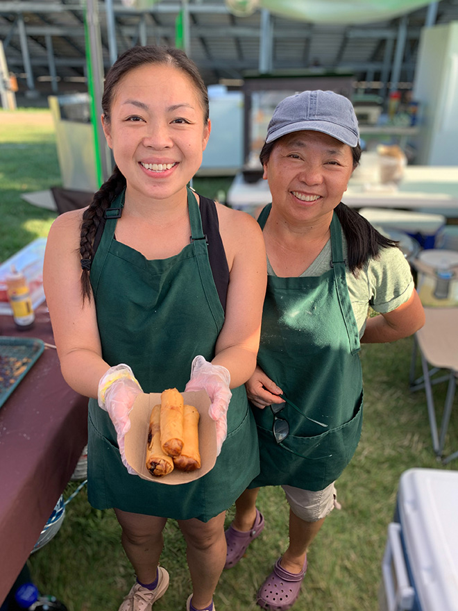 two women from Waffle Jam hand over their pork eggrolls