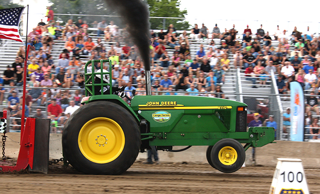 a red International tractor billows smoke as it pulls a sled at the Carver County Fair's NTPA Tractor Pull