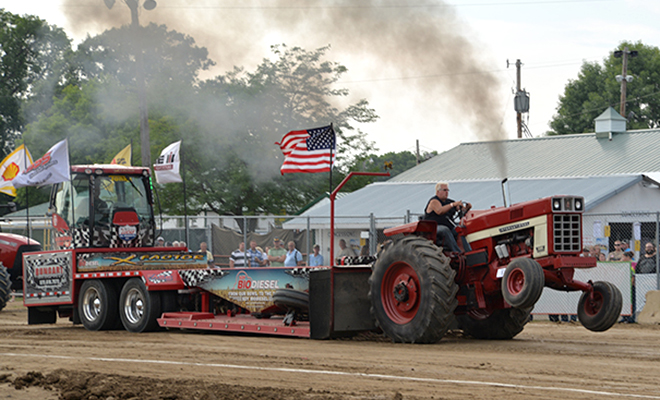 a red tractor does a wheelie at the Carver County Fair Out-of-field Truck & Tractor Pull