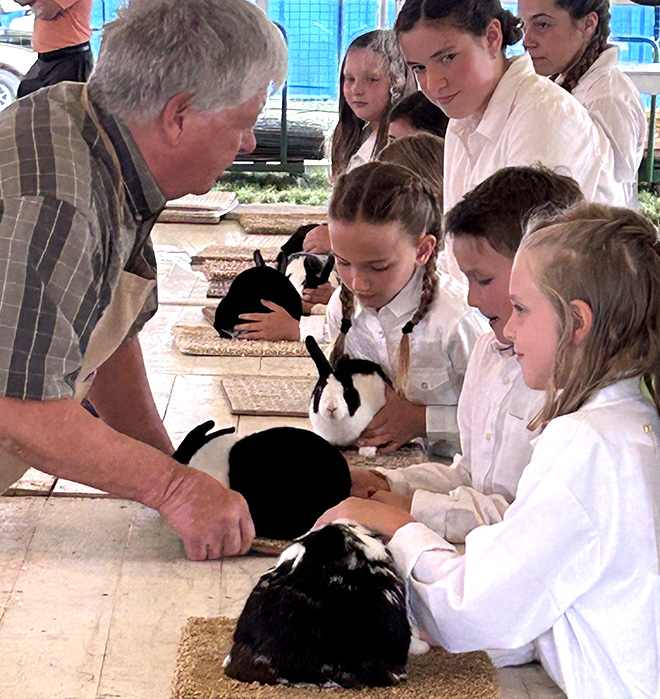 a judge talks to girls showing rabbits at the Carver County Fair