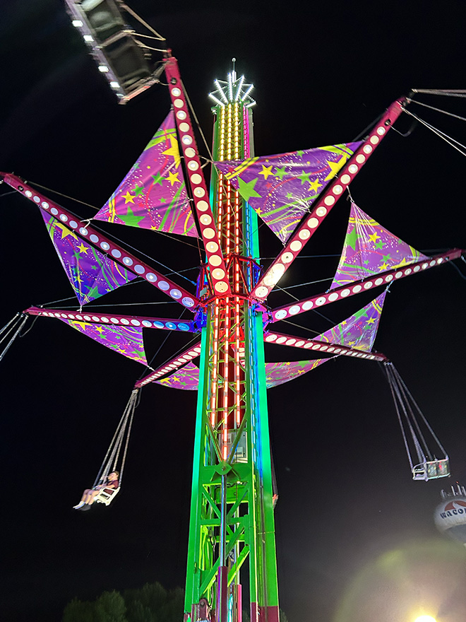 people ride in swings in a Carver County Fair ride at night