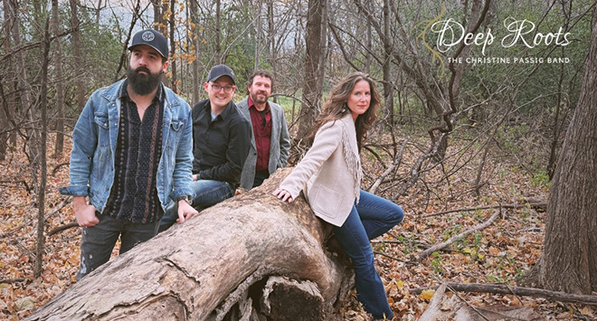 members of the band Deep Roots pose with a felled tree