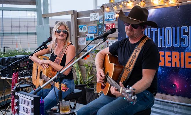 a man a woman with acoustic guitars perform on stage