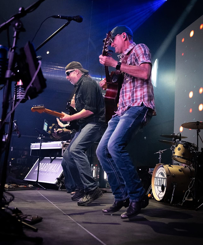 two guitar players jump while performing on stage with Ragtown